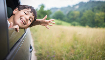 A child leaning their head out of a car window