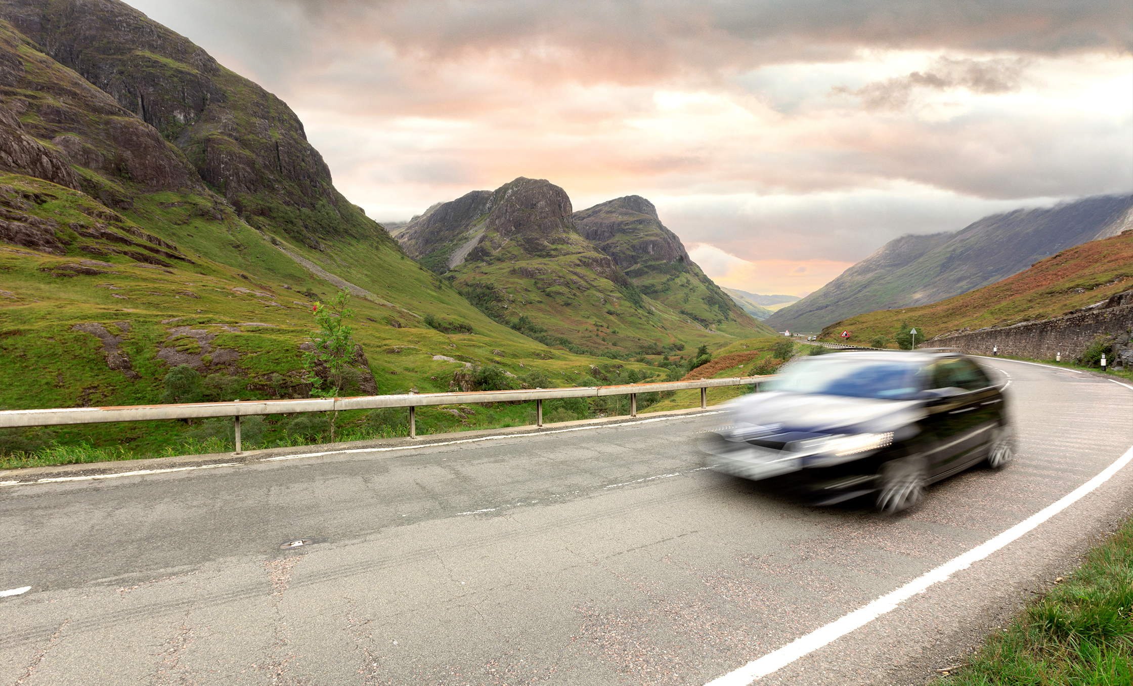 a car driving on a road with mountains in the background