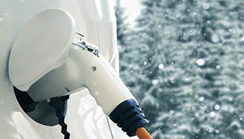 An electric vehicle being charged in a winter climate