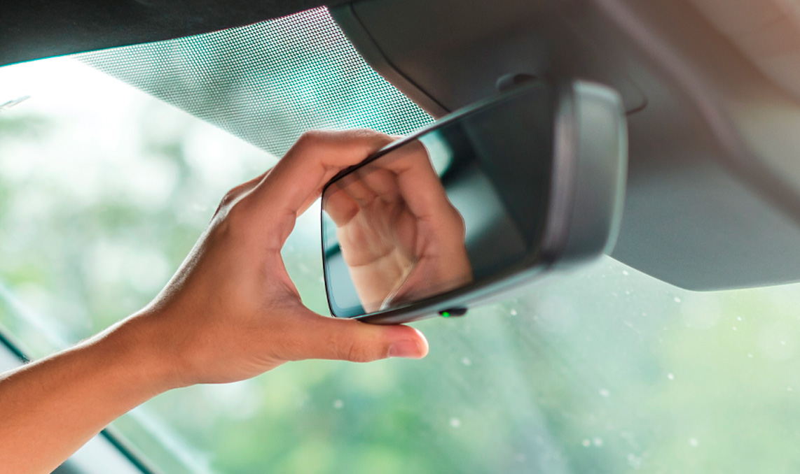 Someone adjusting their rear view mirror