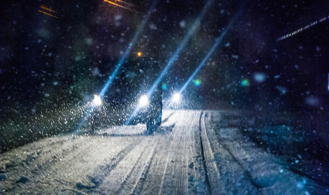 A vehicle driving on a road in the snow