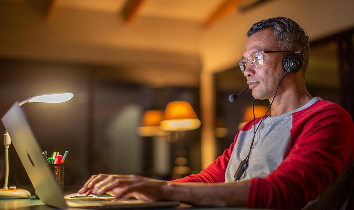 A person working at home on a laptop with a headset on