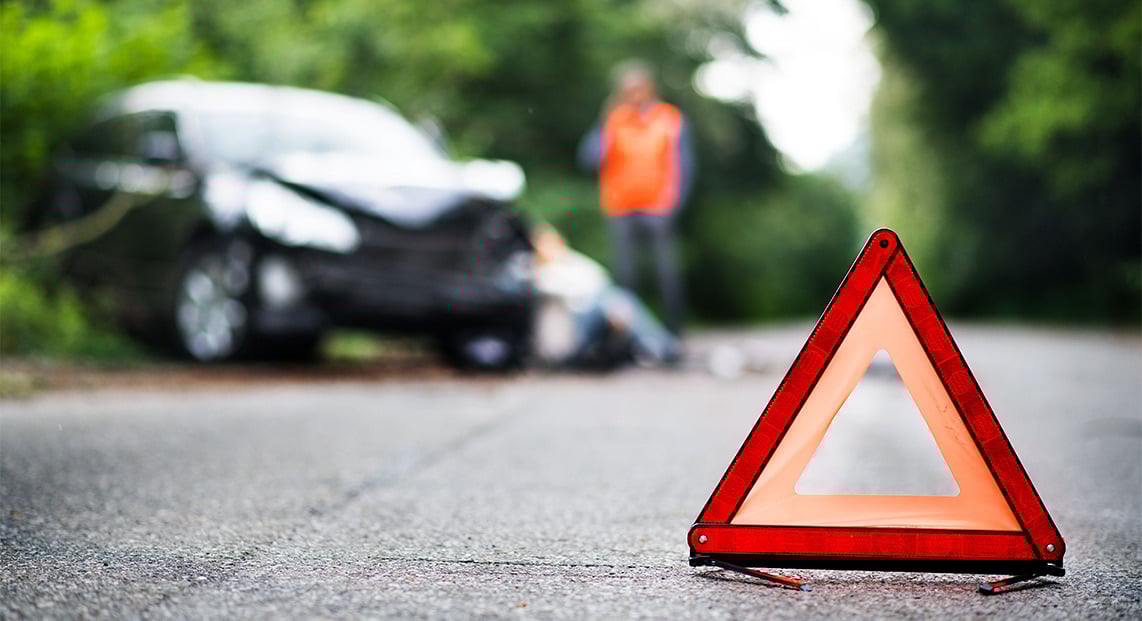 A hazard road marker with an car accident in the background