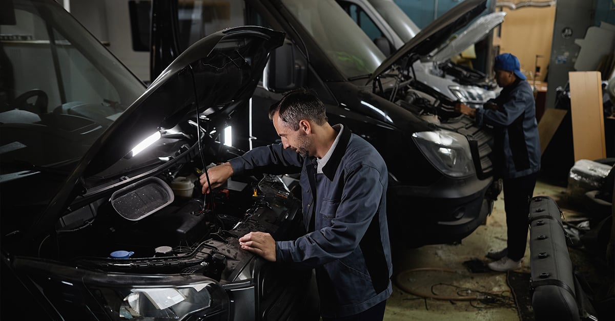 Vehicle service technicians working under the hood of vans