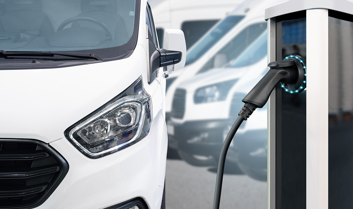 a white van with a black cable plugged into a charging station
