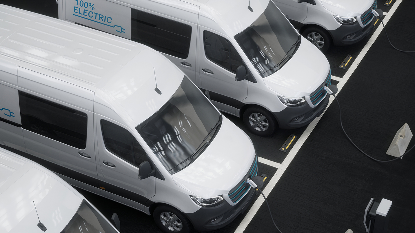 Electric vans parked in a row in a parking lot.