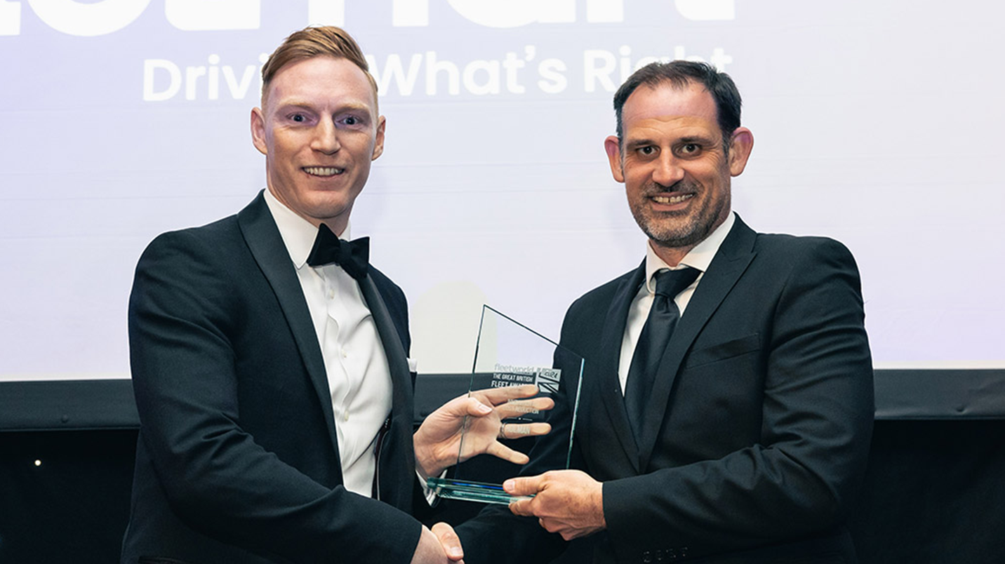 two men in suits shaking hands with a glass award