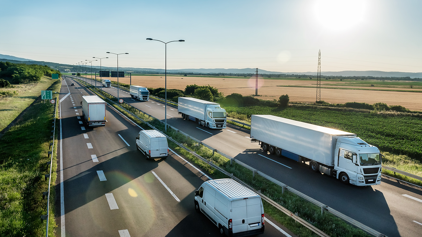 Big rig trucks and work vans driving on a highway.