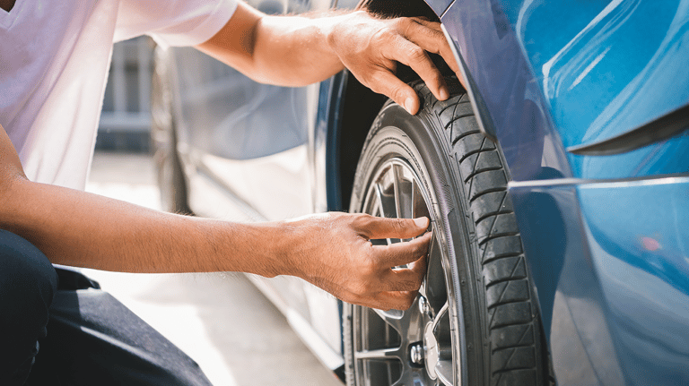 Hands checking a vehicle's tyre.