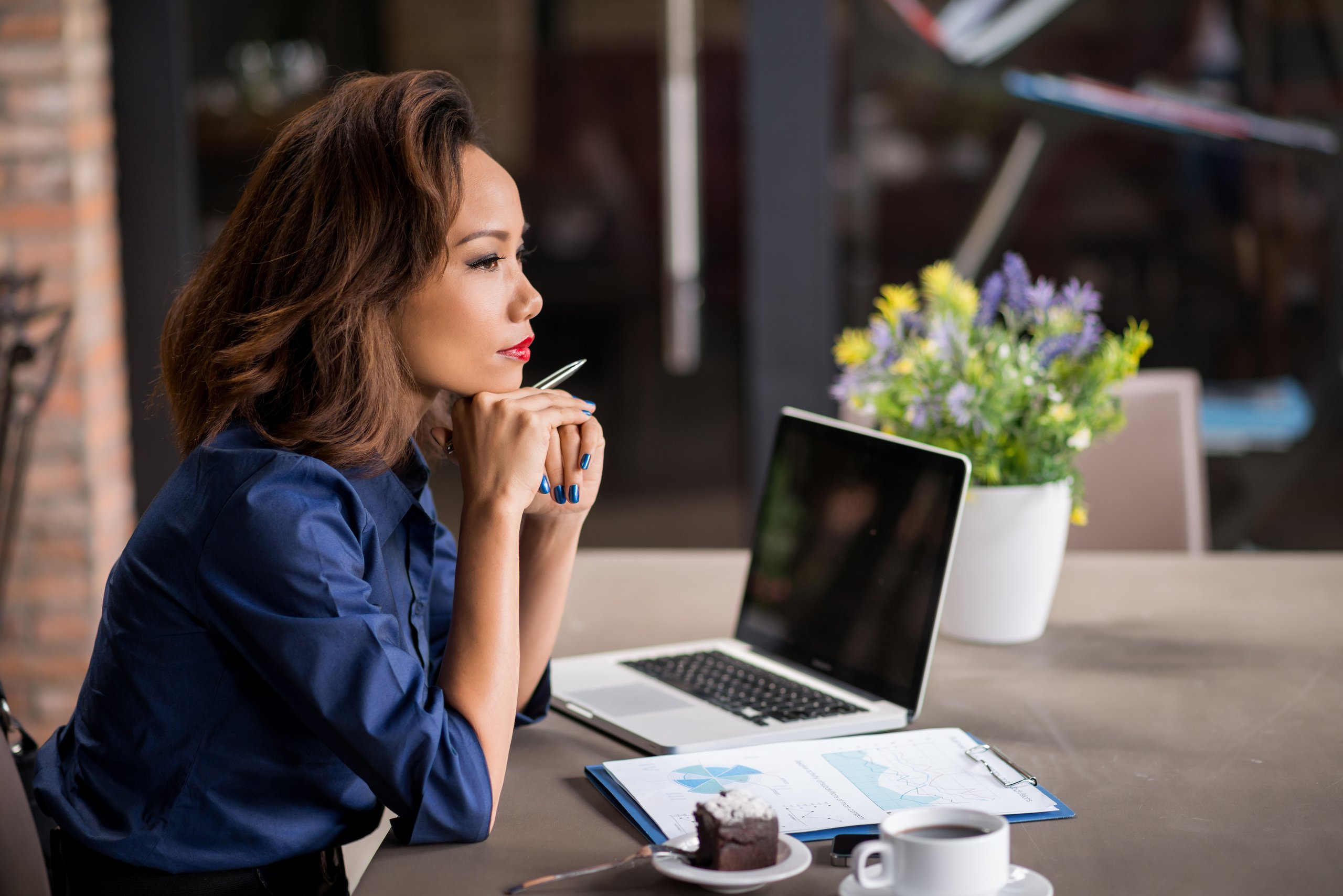 a woman sitting at a table with a laptop and a cup of coffee