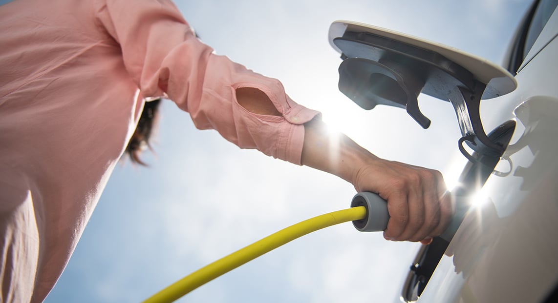 a person holding a hose to a vehicle