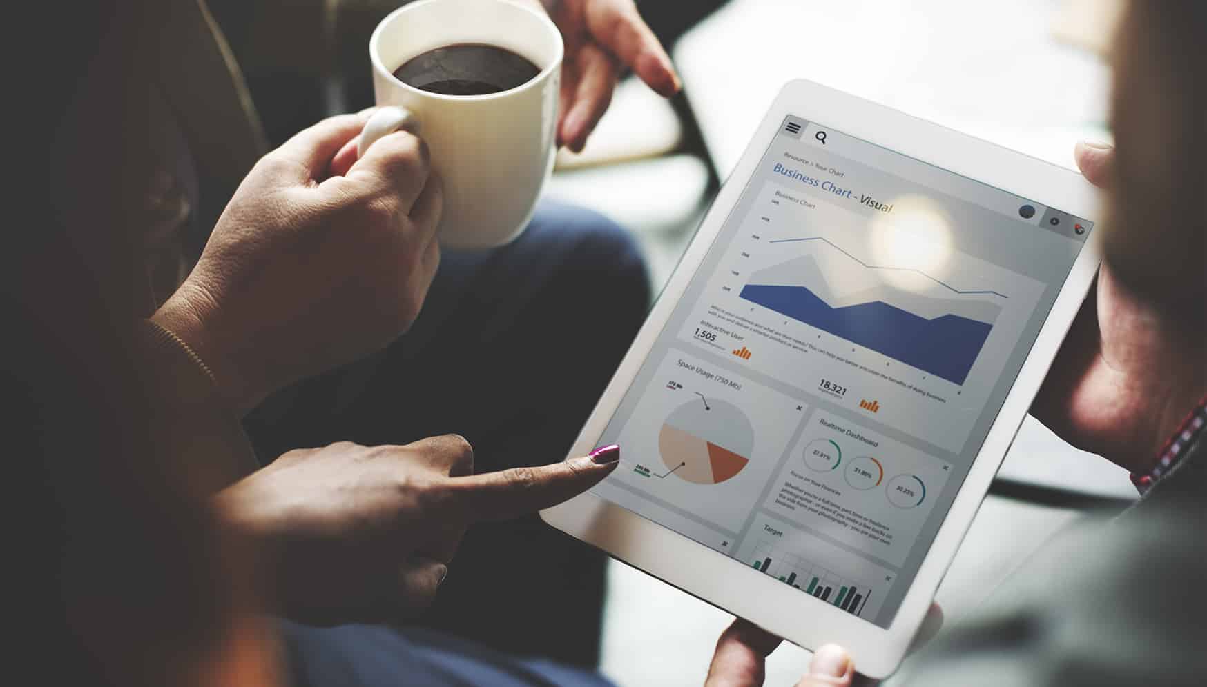 a person holding a cup of coffee and a tablet