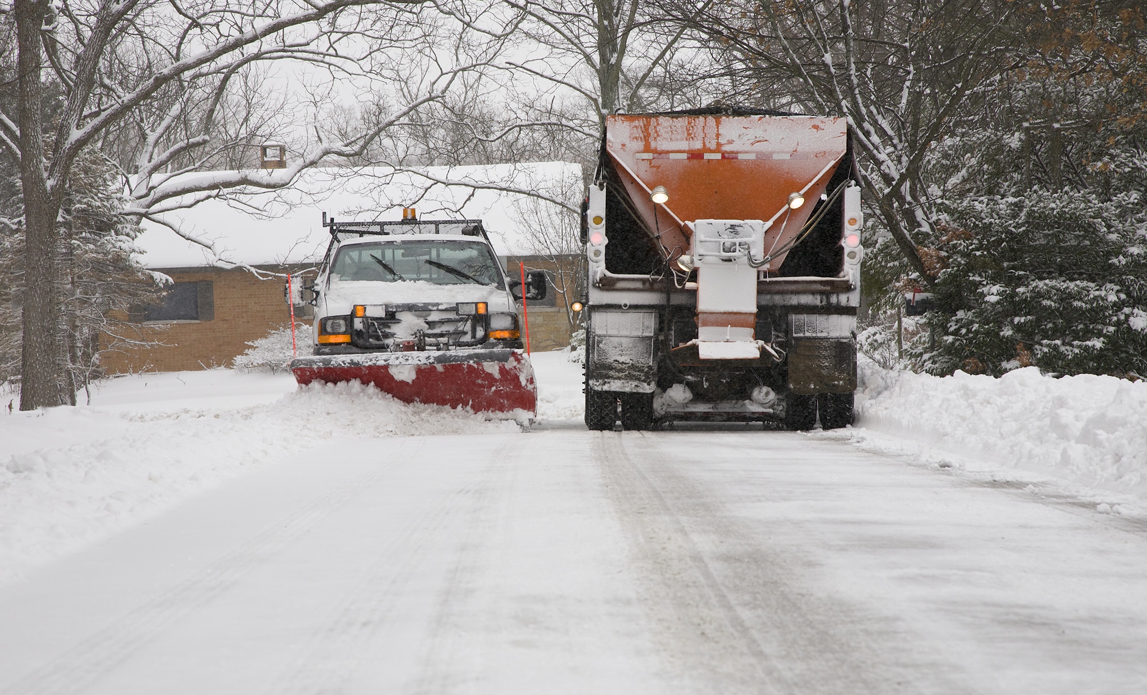 a snow plow and a truck on a snowy road
