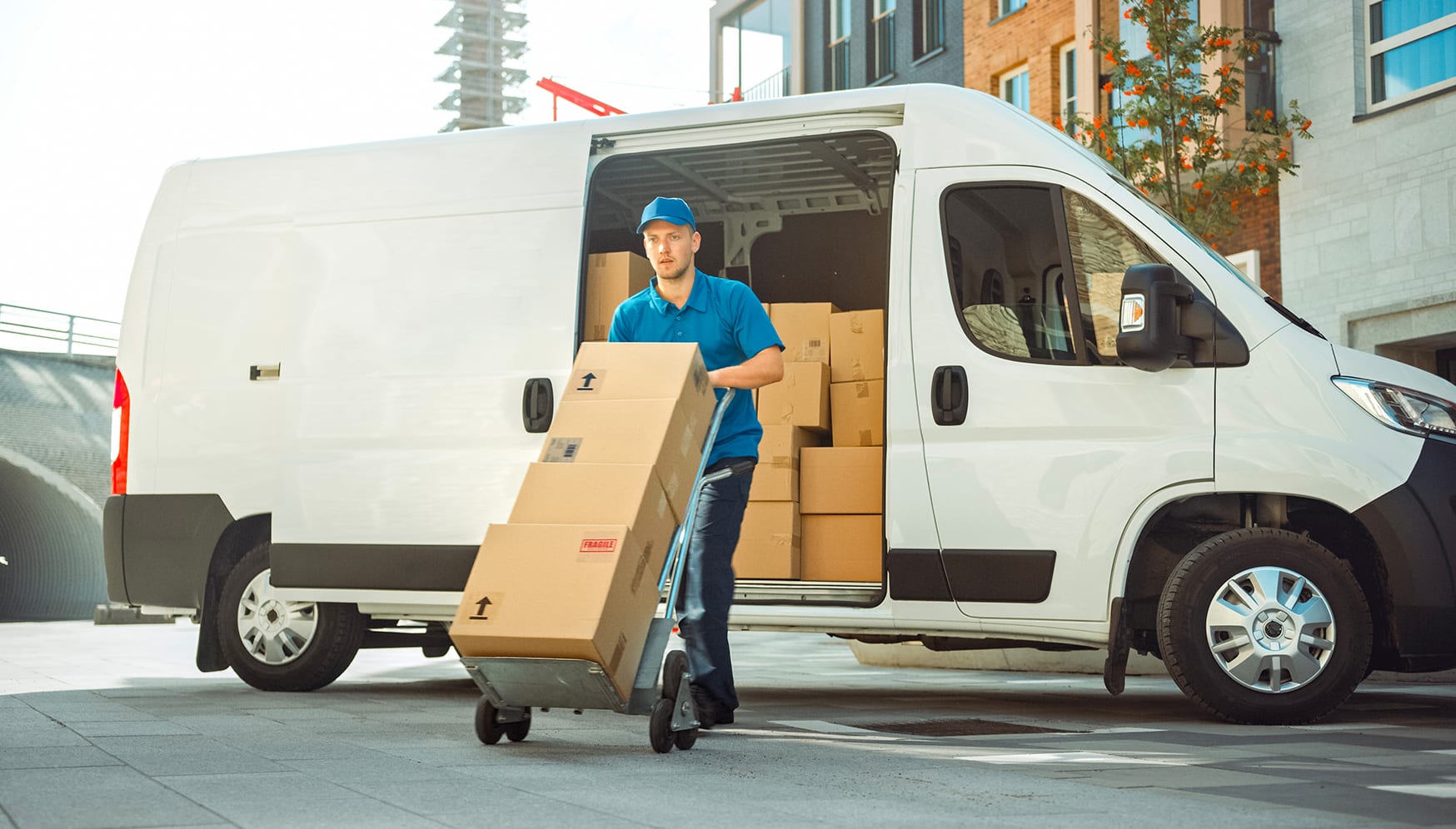 a man pushing a cart with boxes in the back of a van