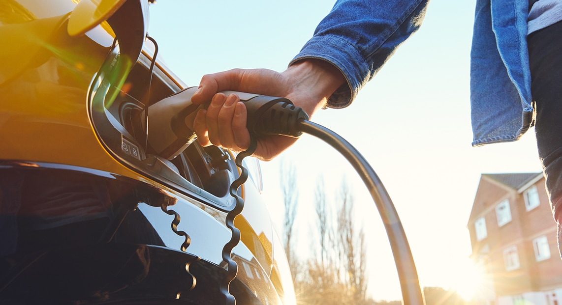 a person holding a fuel nozzle to a car