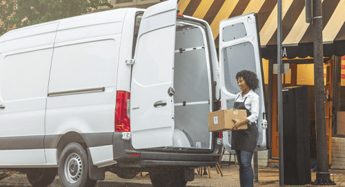 a woman holding a box and opening the van