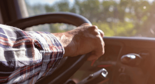 a hand on a steering wheel