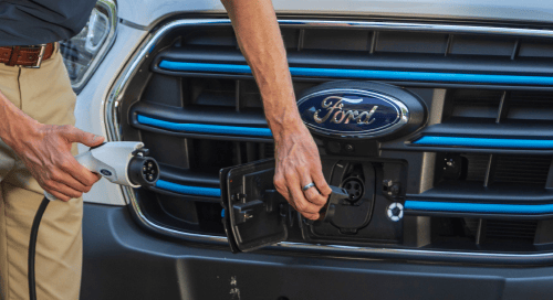 a hand holding a plug in to a car