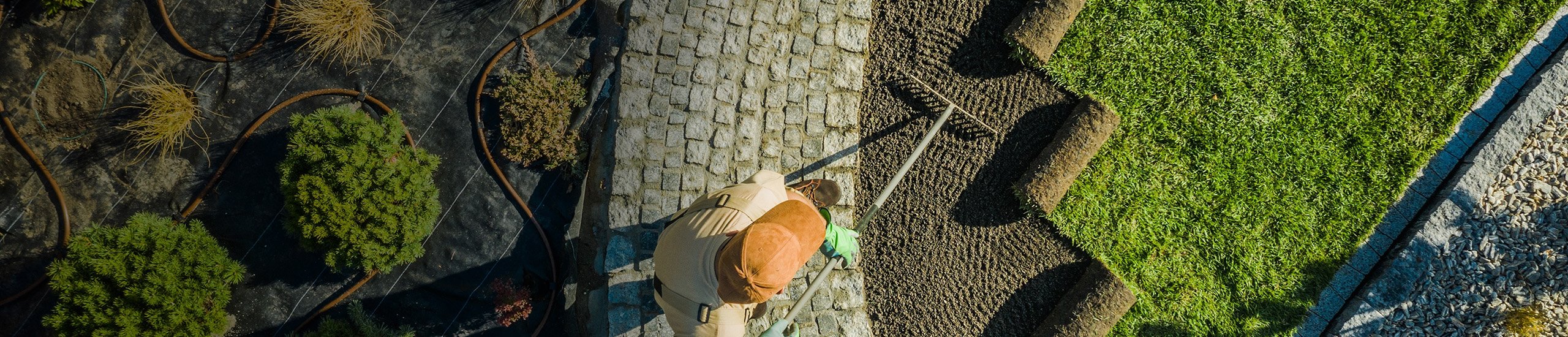 a person with a rake on a cobblestone path