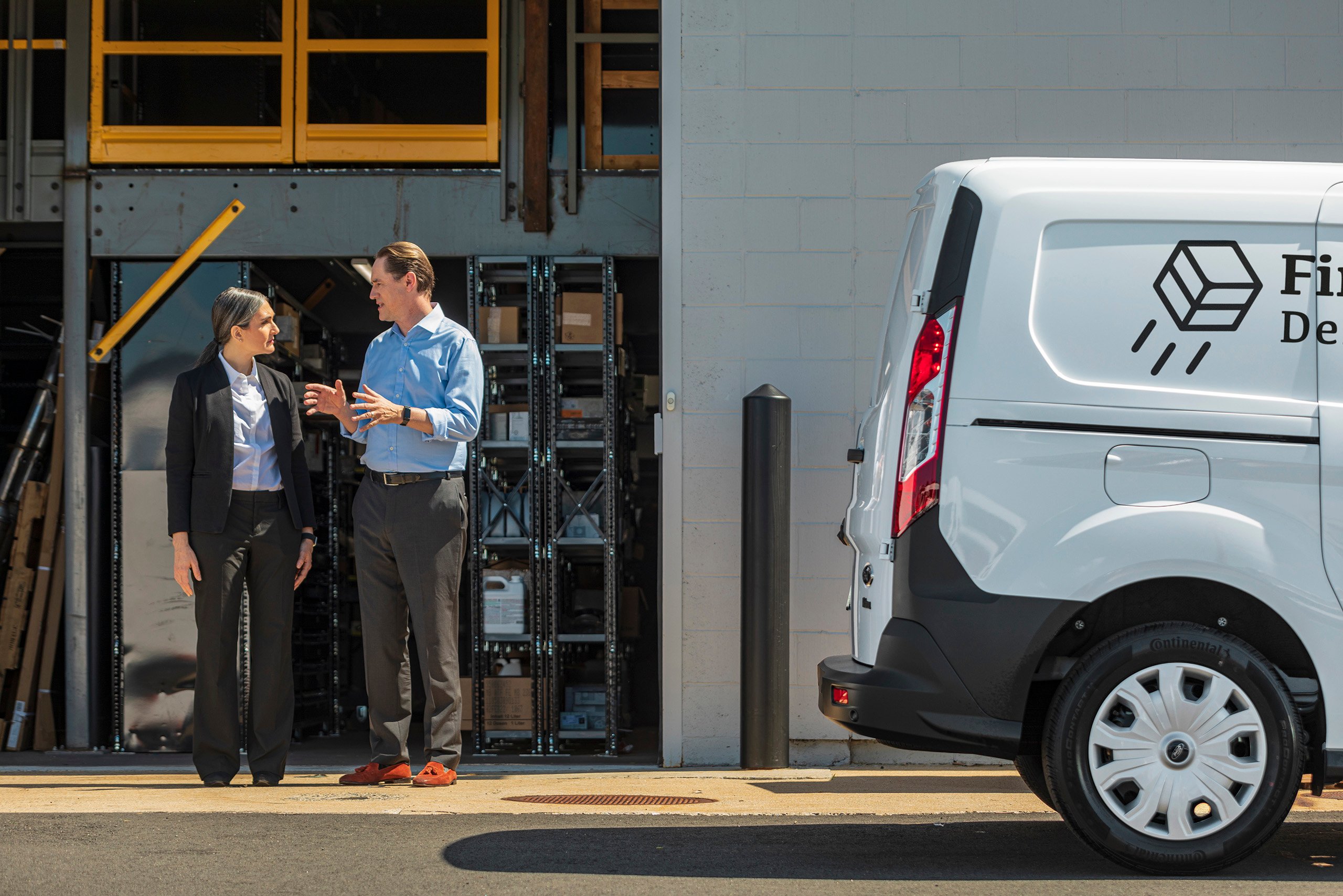 a man and woman standing outside of a warehouse