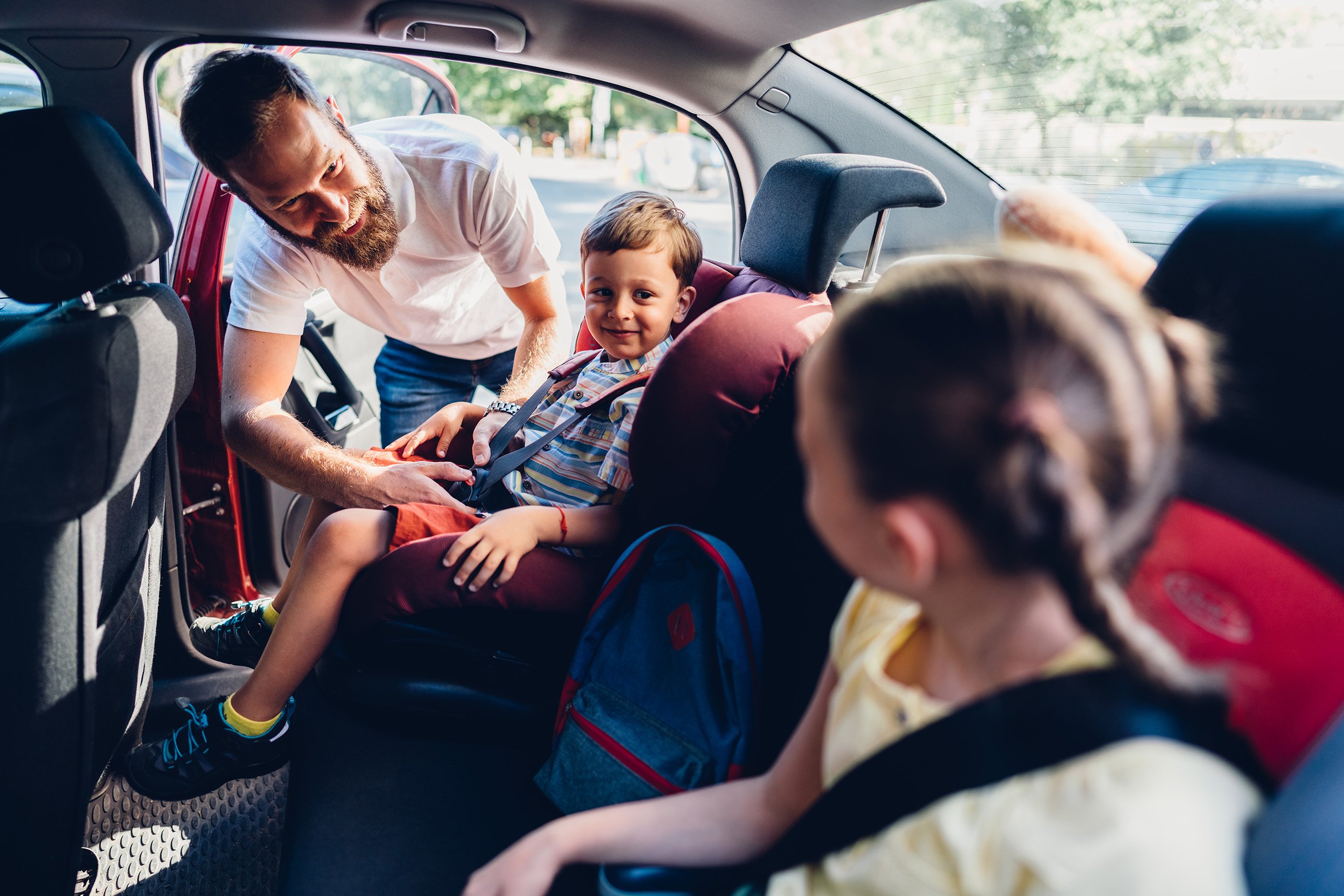 a man helping a child in a car seat