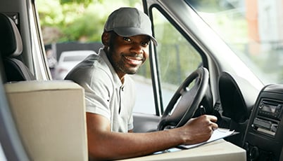 a man in a cap sitting behind a car
