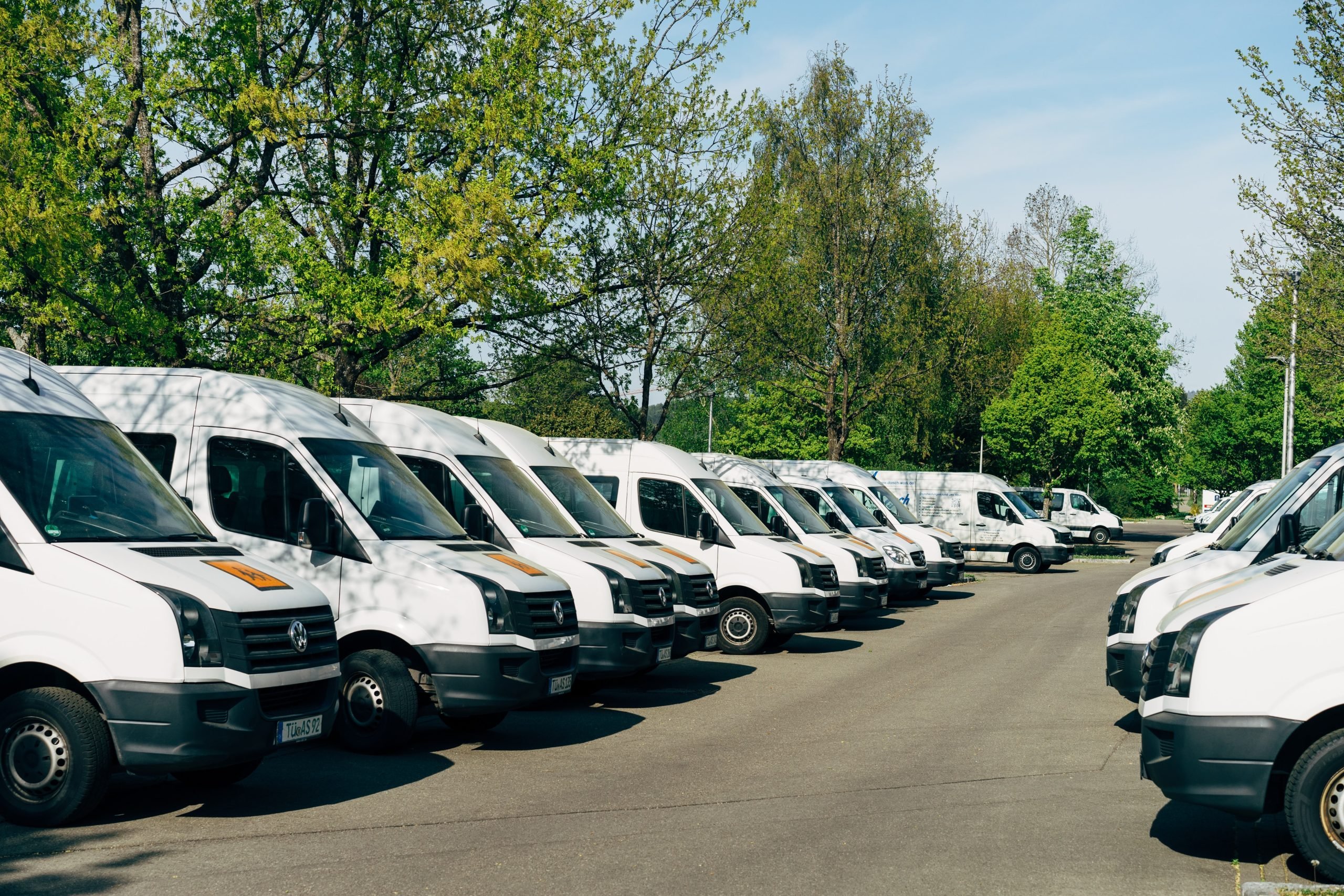a group of white vans parked in a parking lot