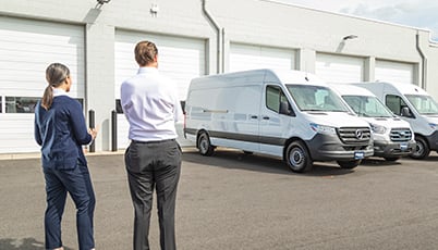 a man and woman standing in front of a white van