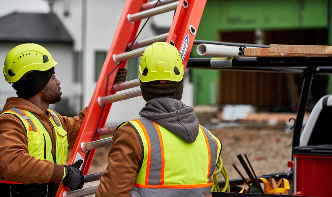 construction workers holding a ladder