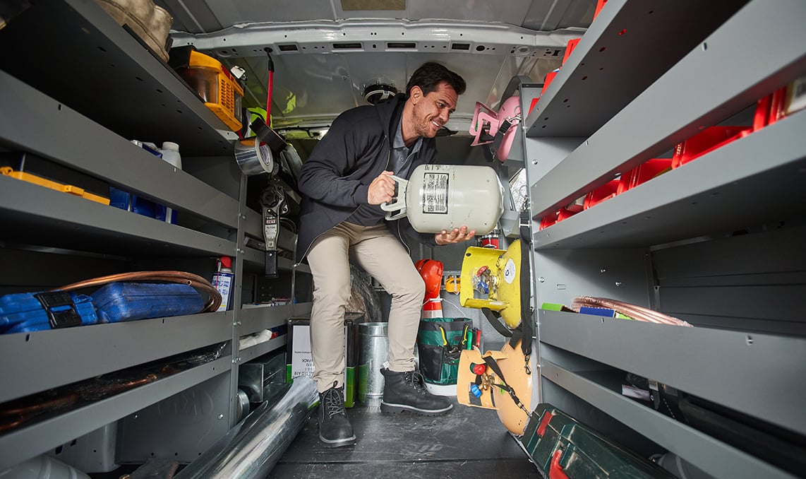 An hvac professional moving a tank in the back of an upfitted van