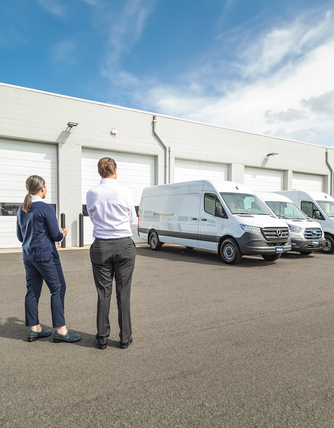 a man and woman standing in front of white vans