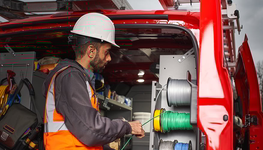 A telecom worker getting material from an upfitted van