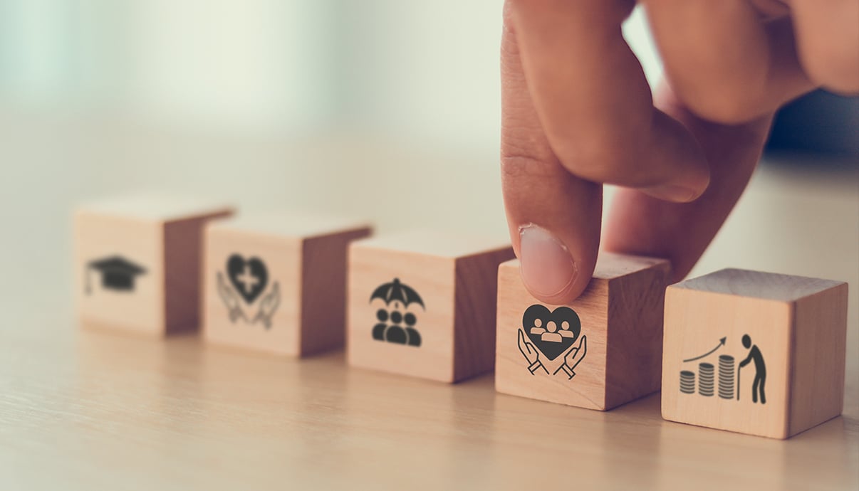 A hand organizing wooden blocks featuring business icons.
