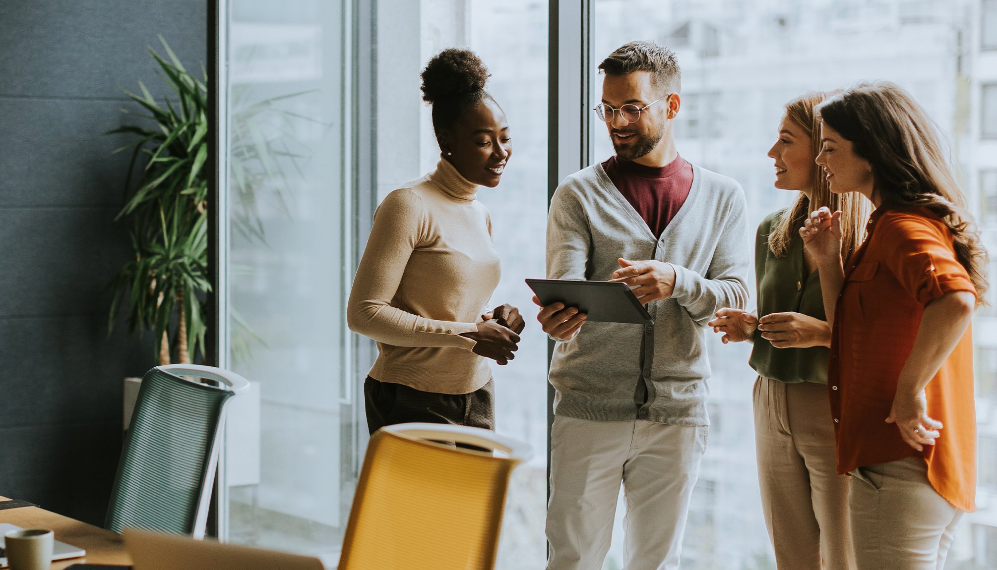 a group of professionals grouped together looking at a tablet.