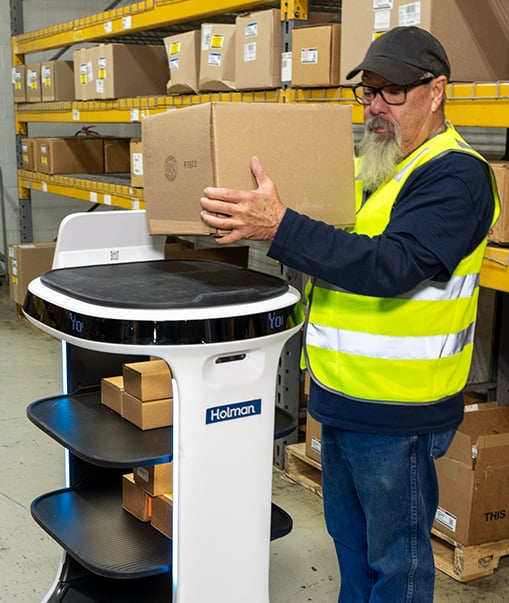 Man using robotic cart in warehouse.