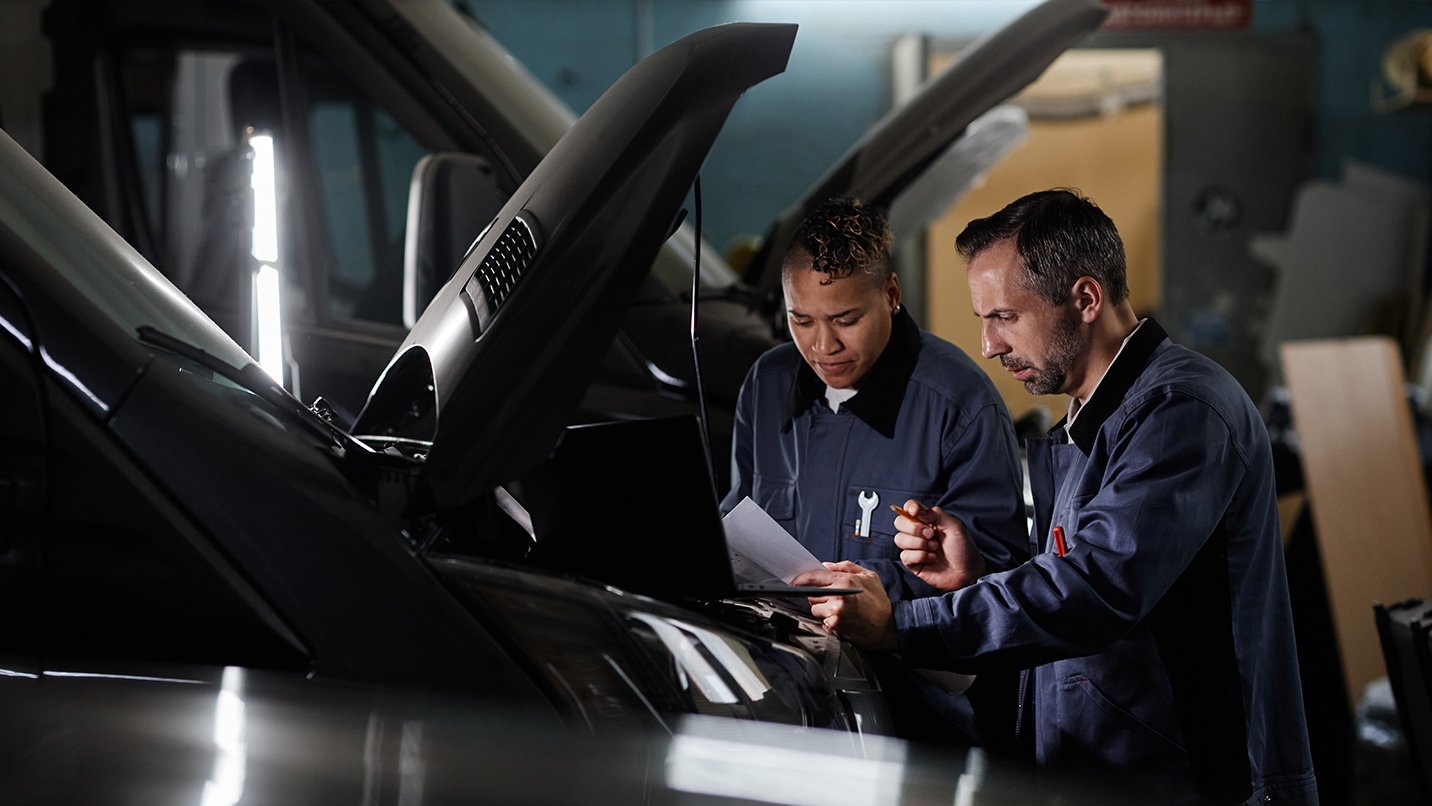 Two mechanics inspecting vehicle engine