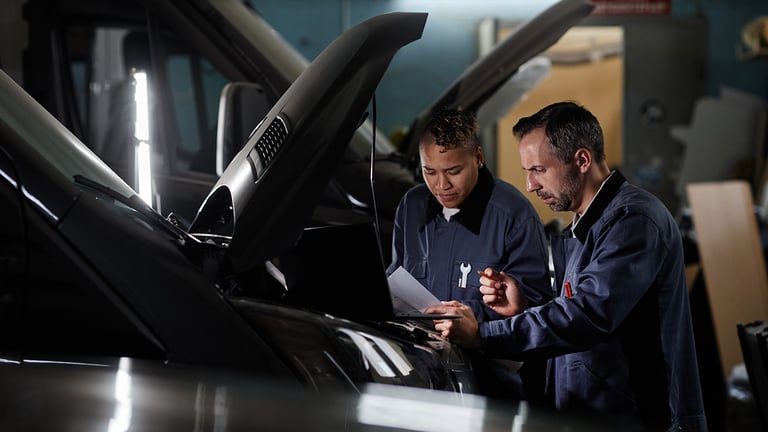 Two mechanics inspecting vehicle engine