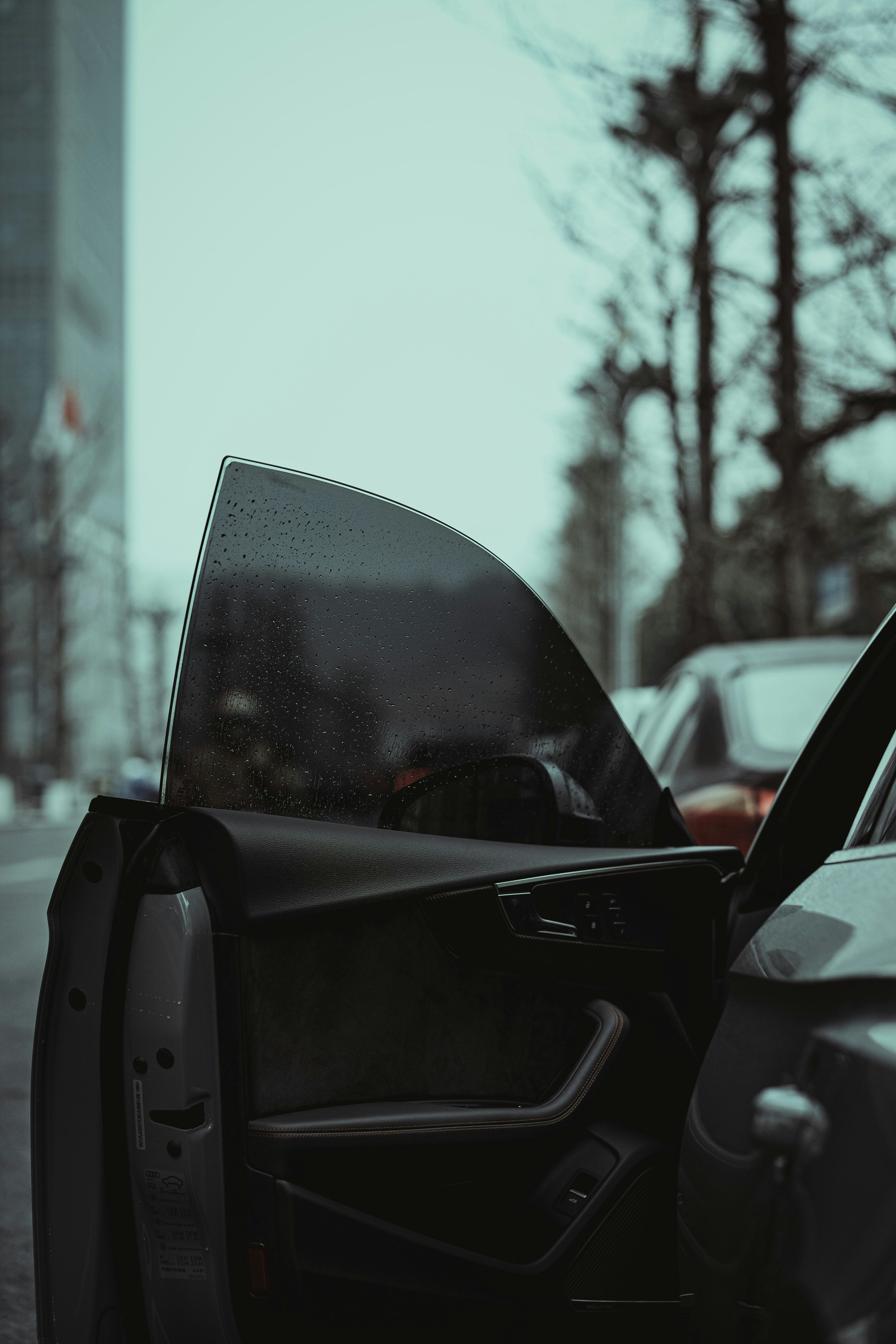 Close-up of an open car door on a wet city street