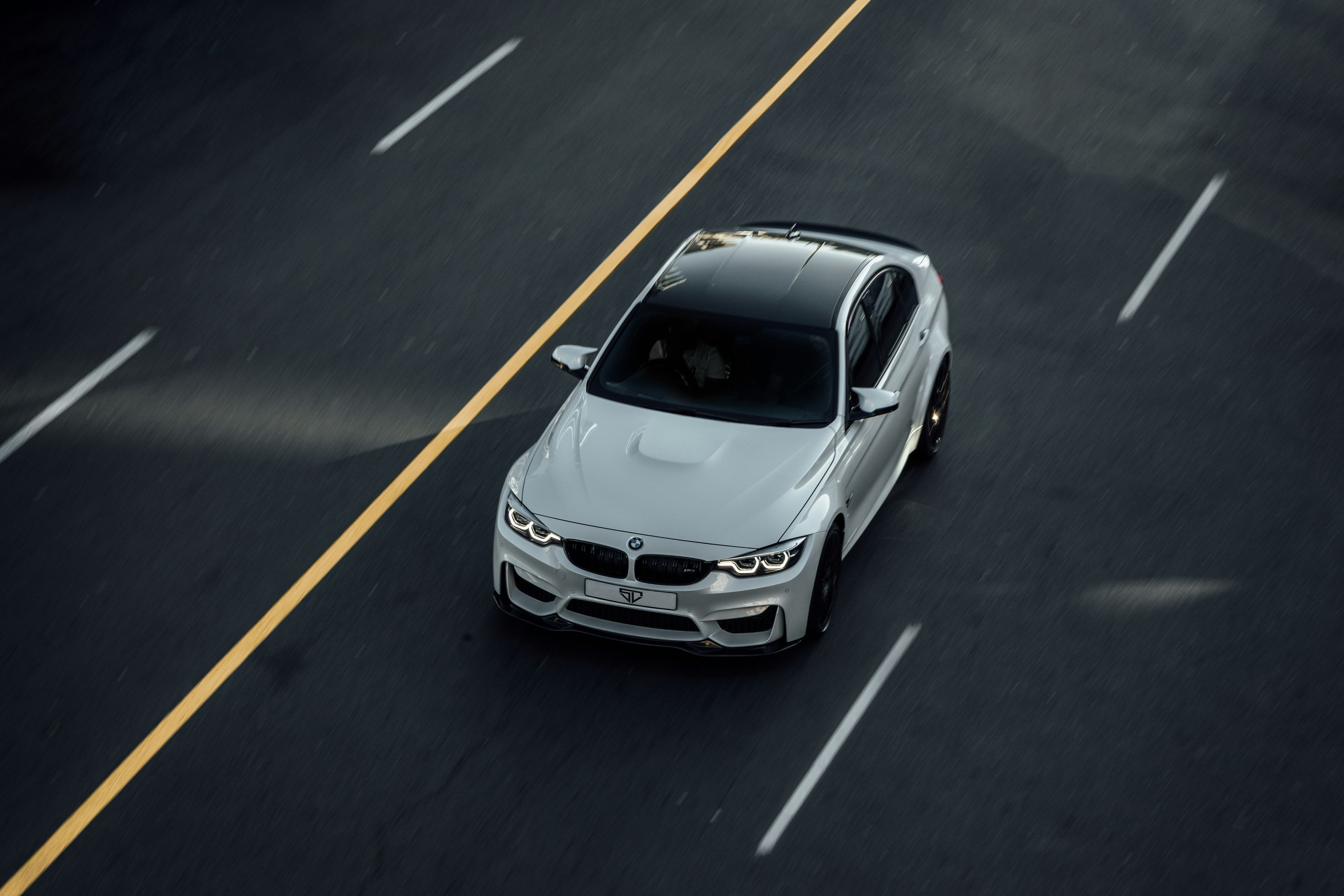 White BMW saloon shot from above driving with motion blur