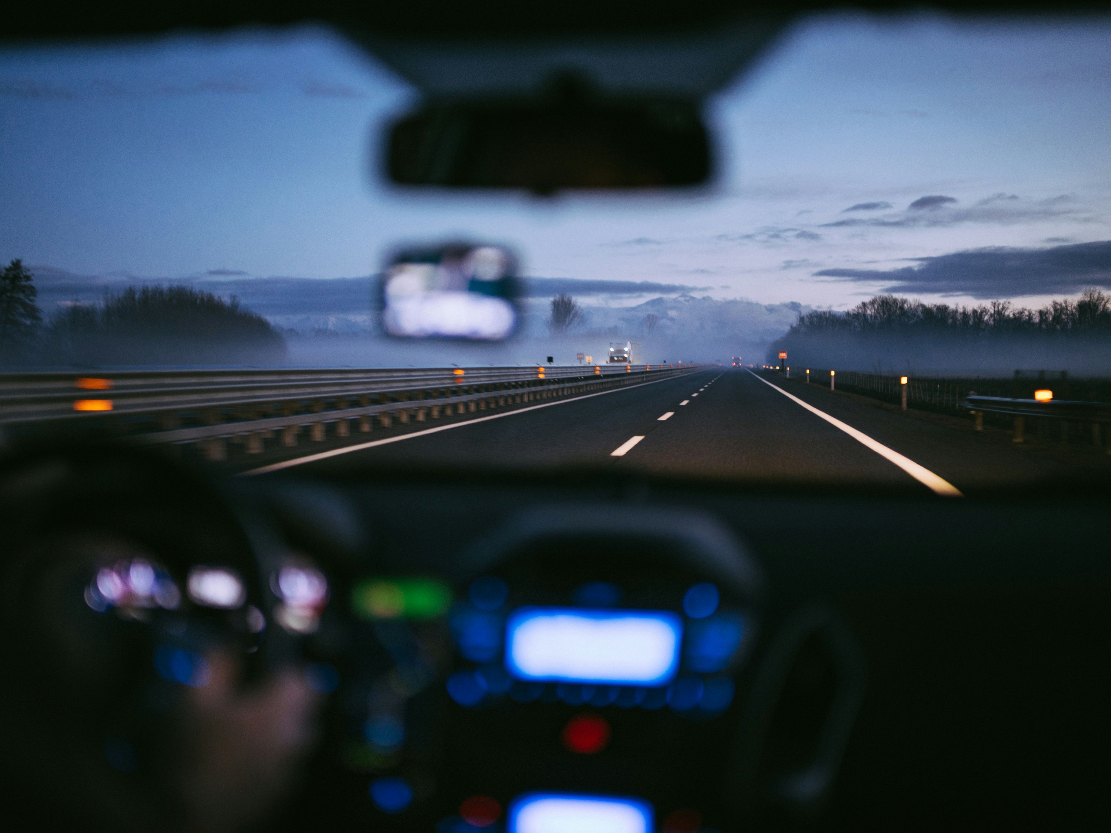 Driver-eye view through windscreen onto a misty motorway at dusk