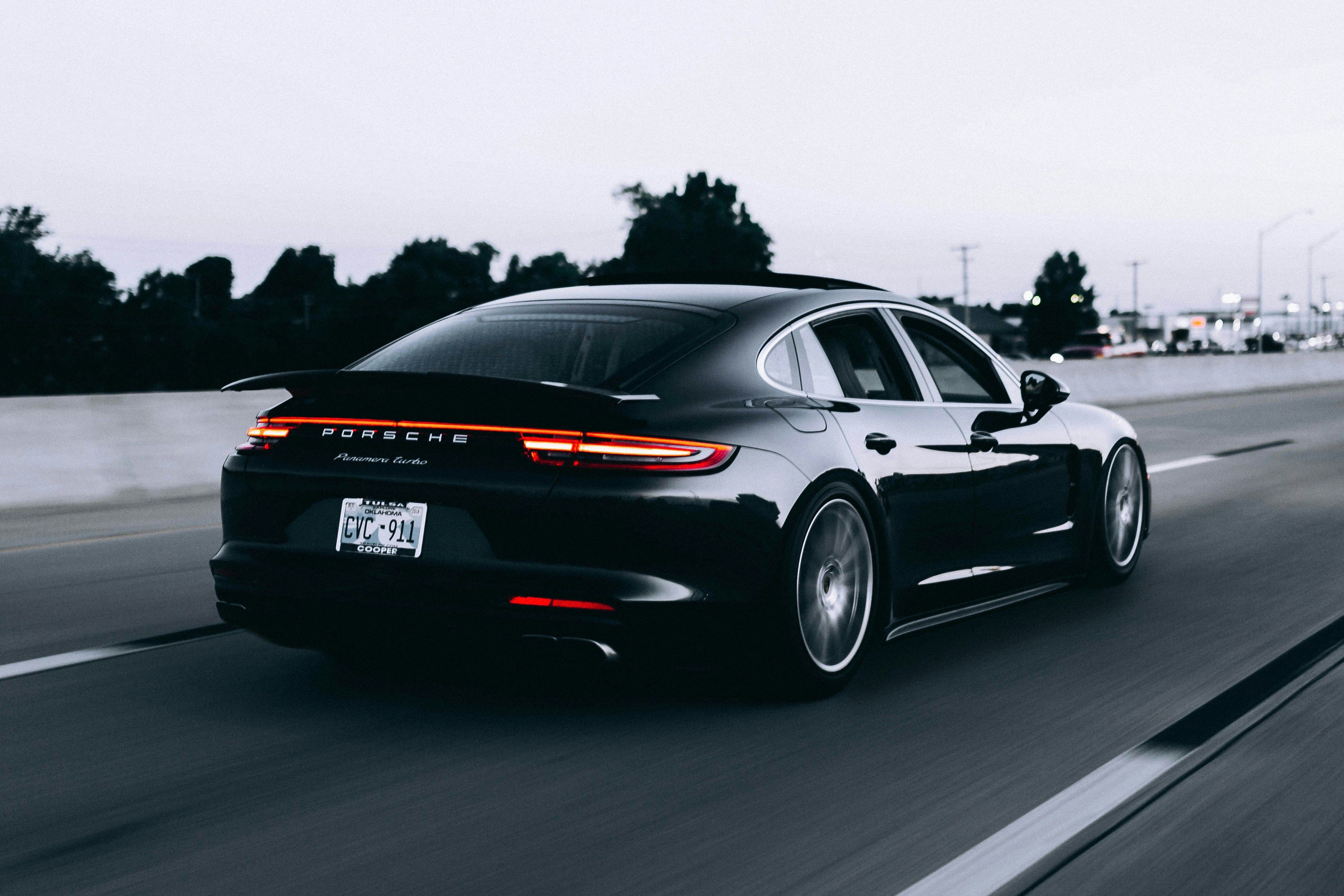 Black Porsche Panamera in motion on a highway, rear view