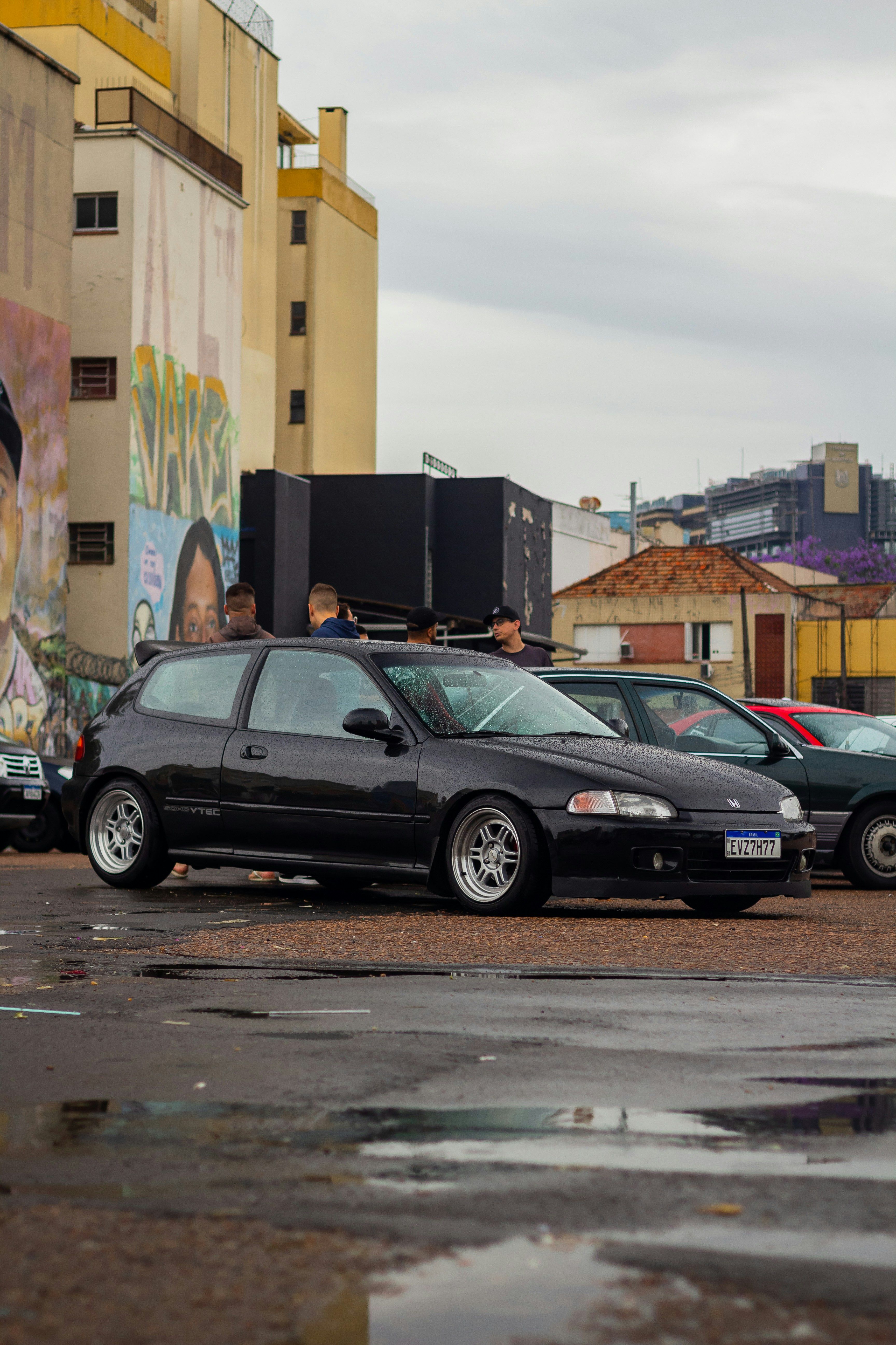 Modified black Honda Civic in an urban car park with street art