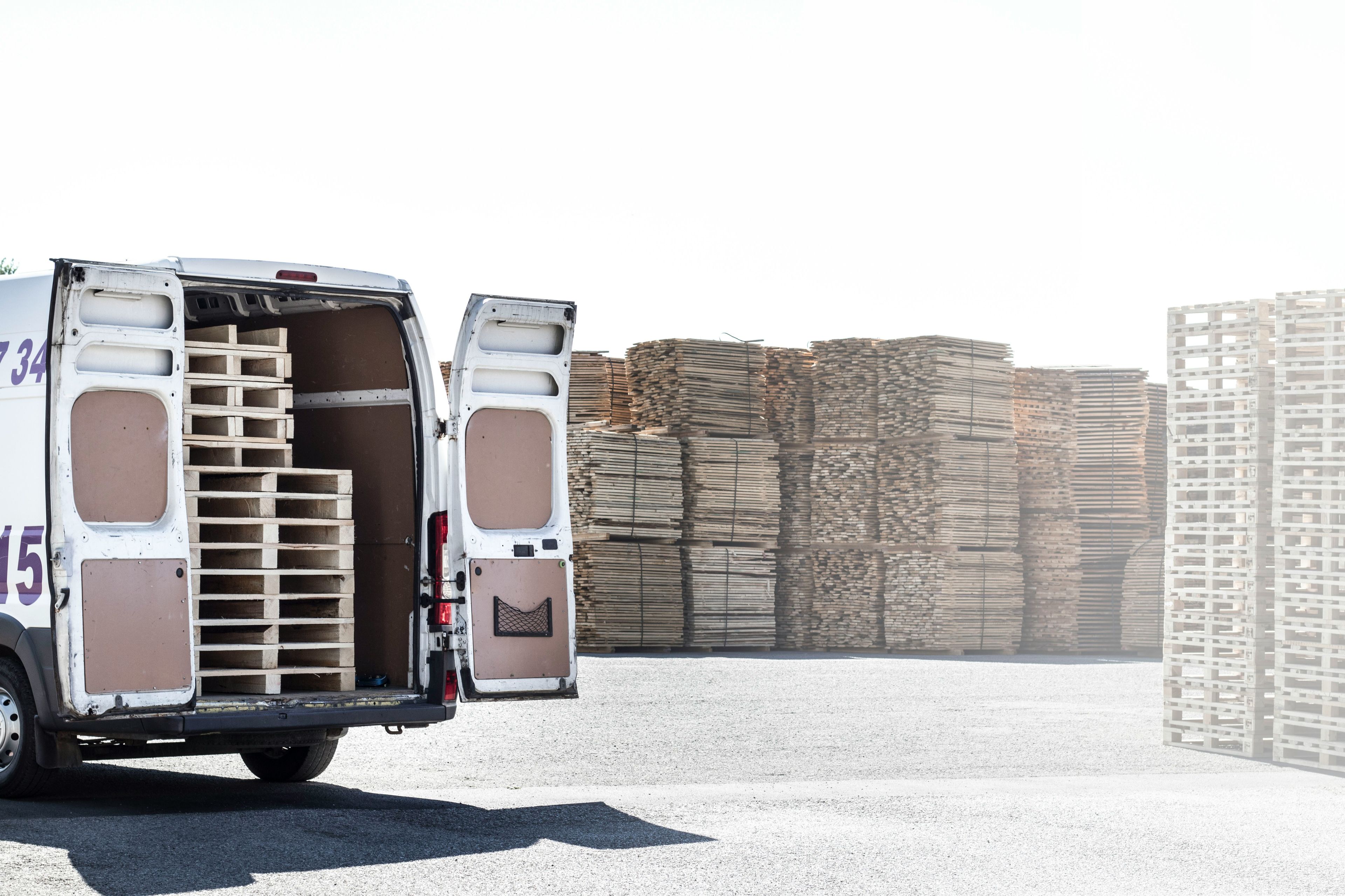 White panel van with rear doors open, loaded with wooden pallets