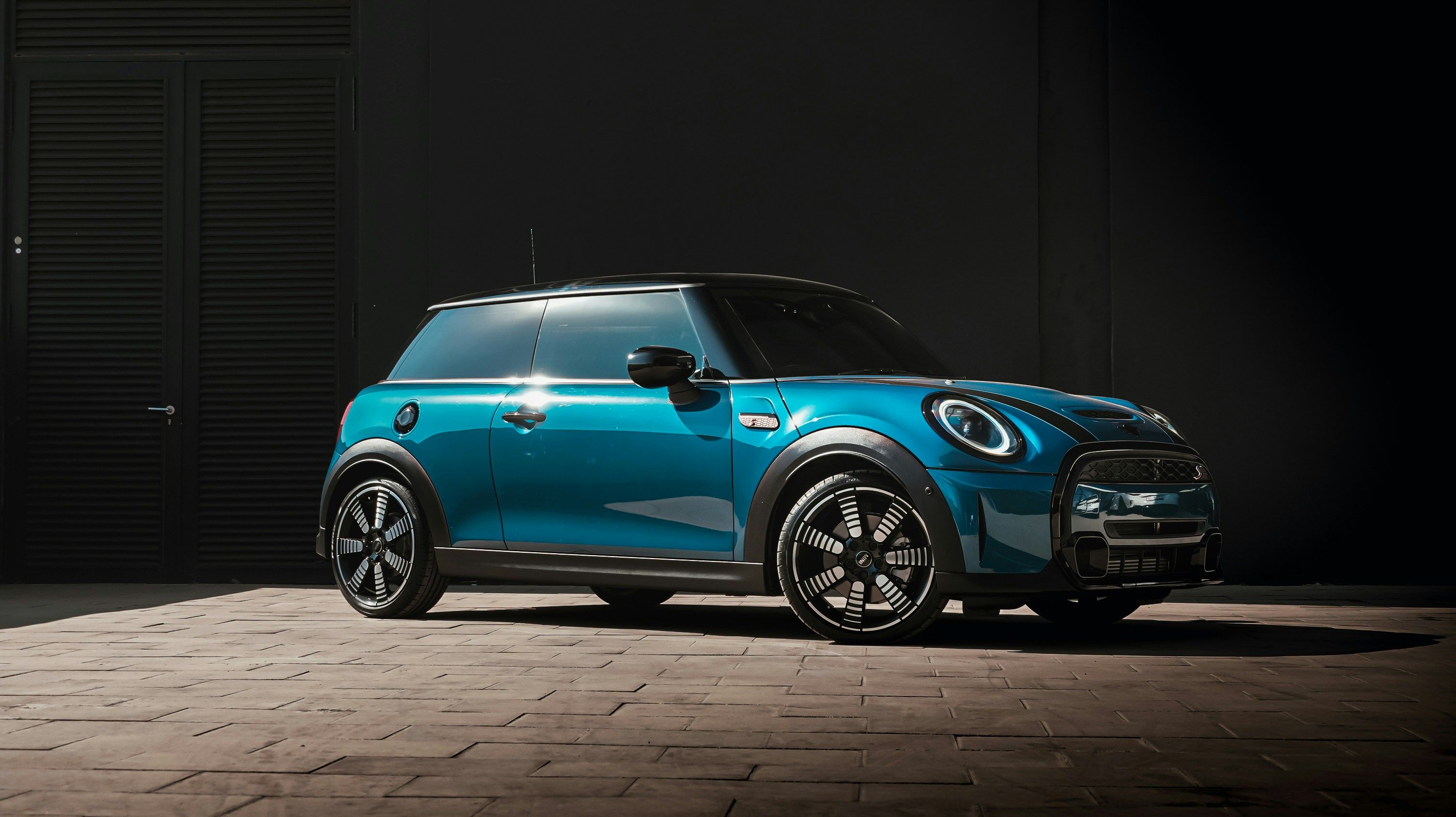 Teal MINI Cooper Electric in dramatic dark studio lighting