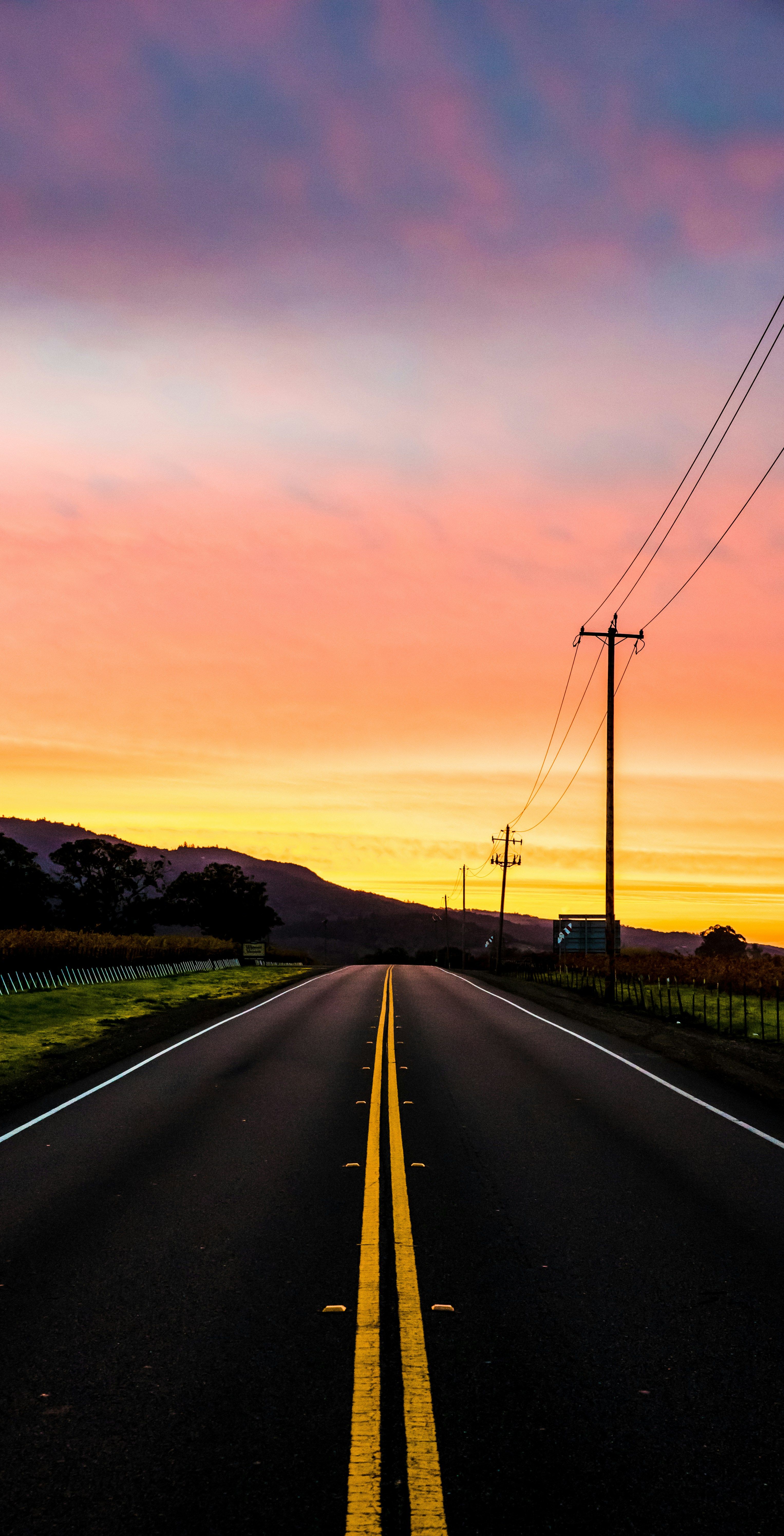Open road leading toward a vivid pink-and-orange sunset sky