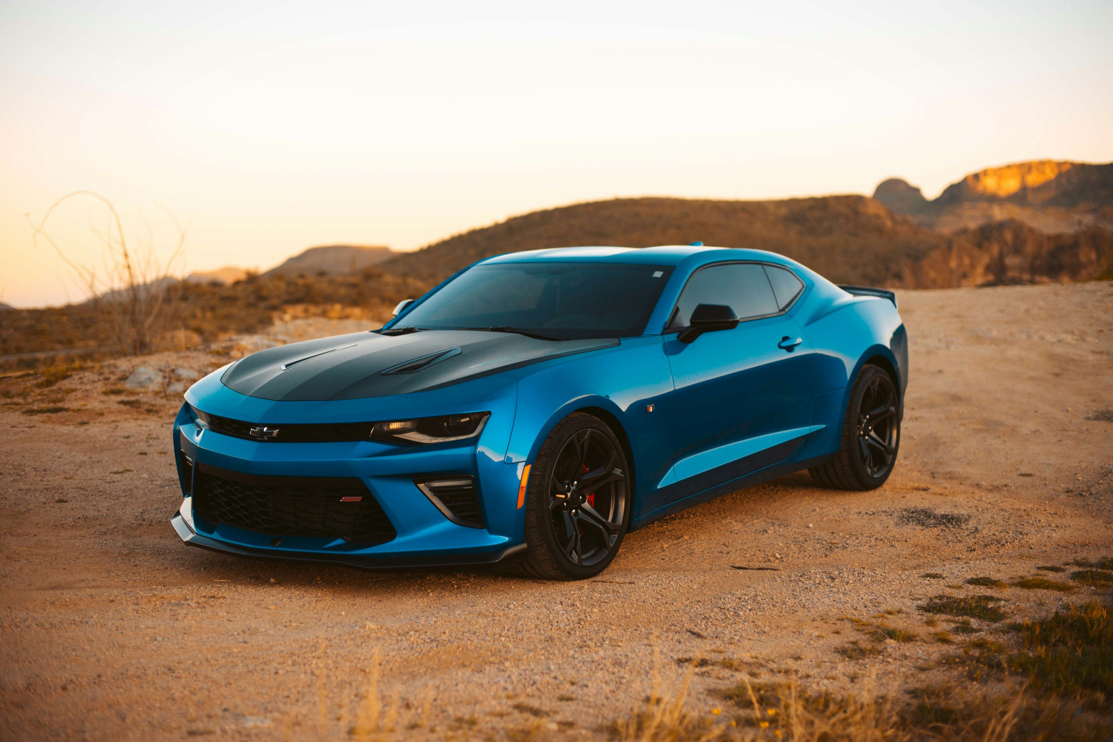Blue Chevrolet Camaro coupe parked in the desert at sunset