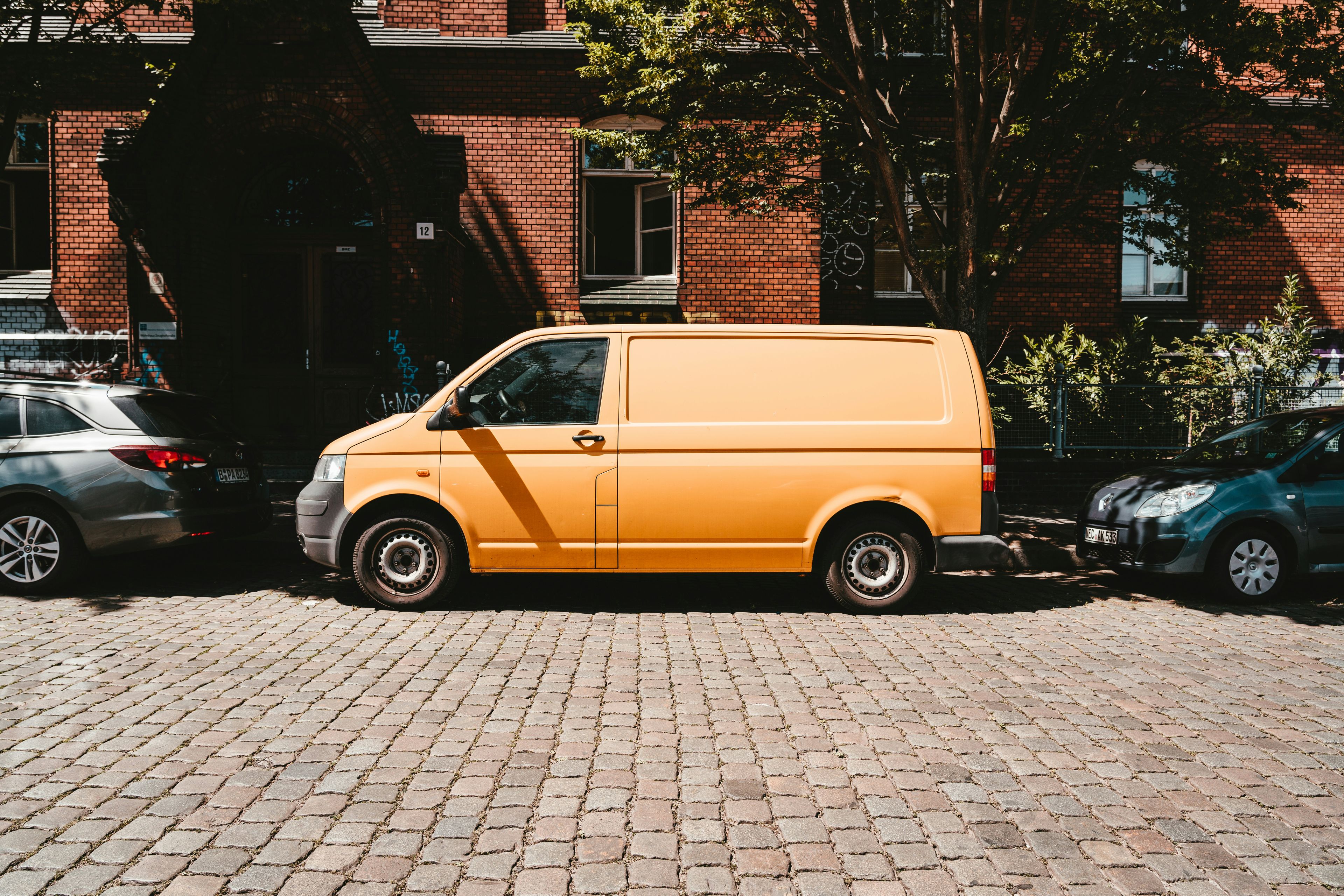 Orange VW Transporter panel van parked on a cobbled street