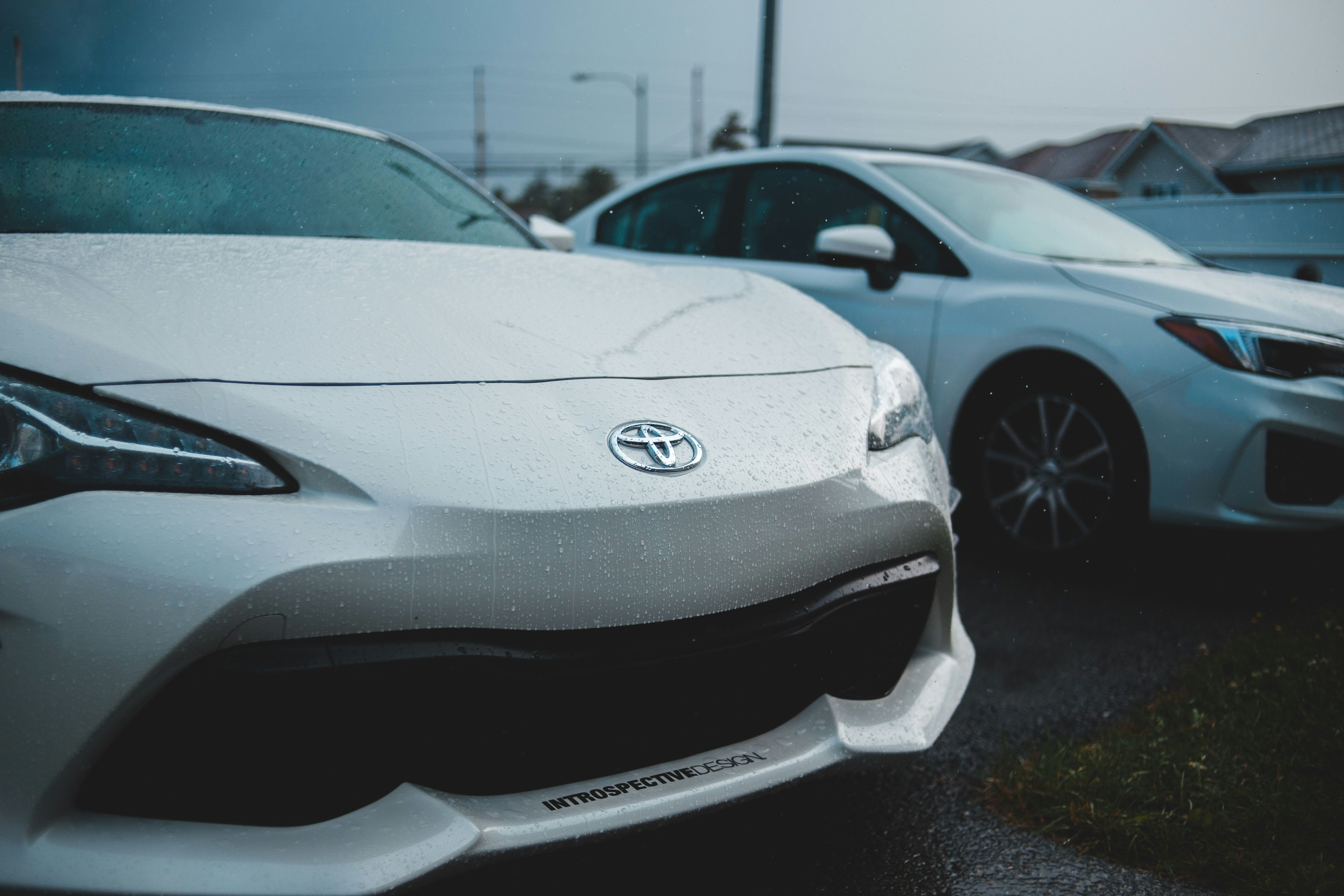 Close-up front-end detail of a white coupe covered in rain droplets