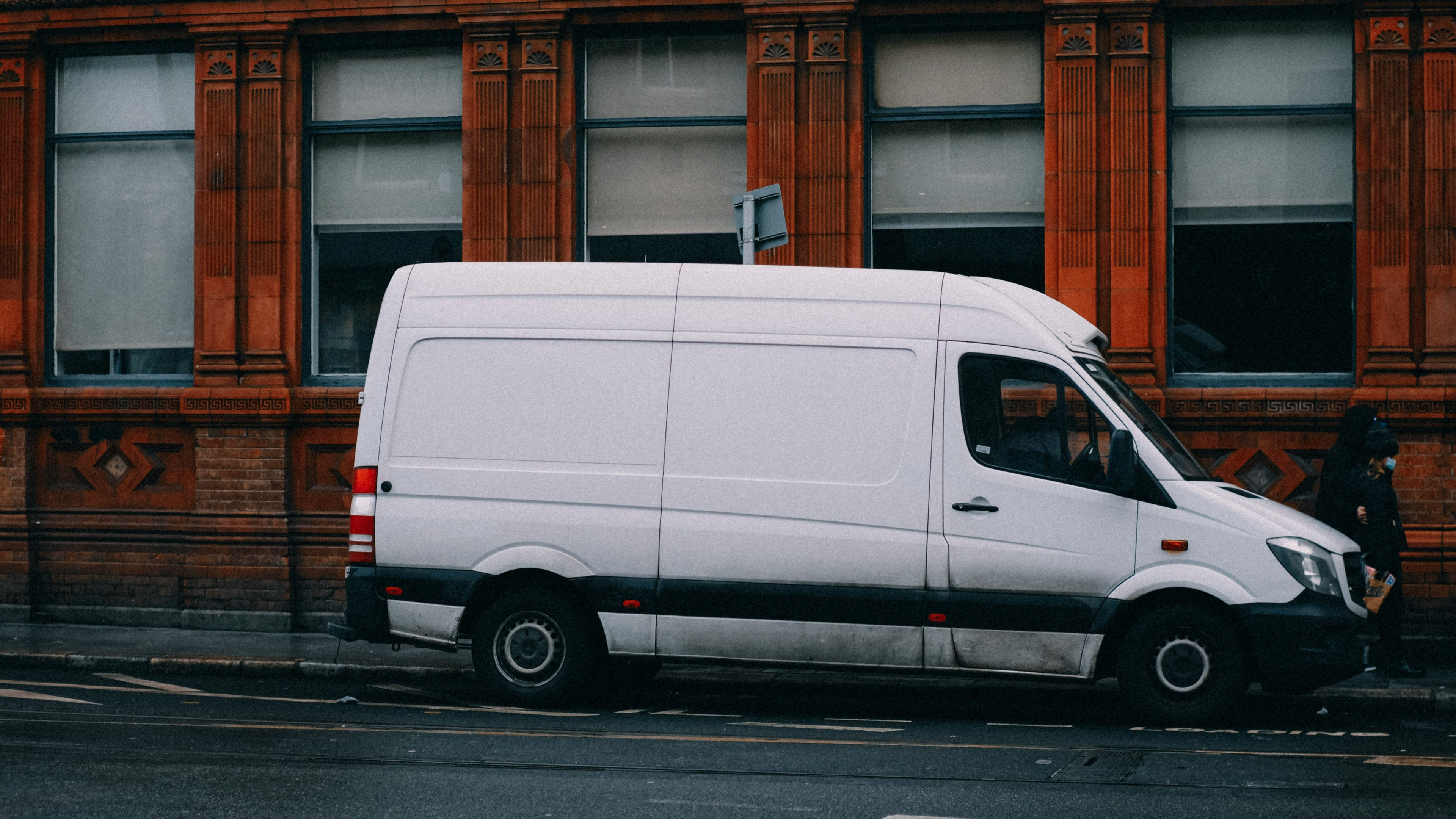 White Mercedes Sprinter panel van parked on a red-brick city street