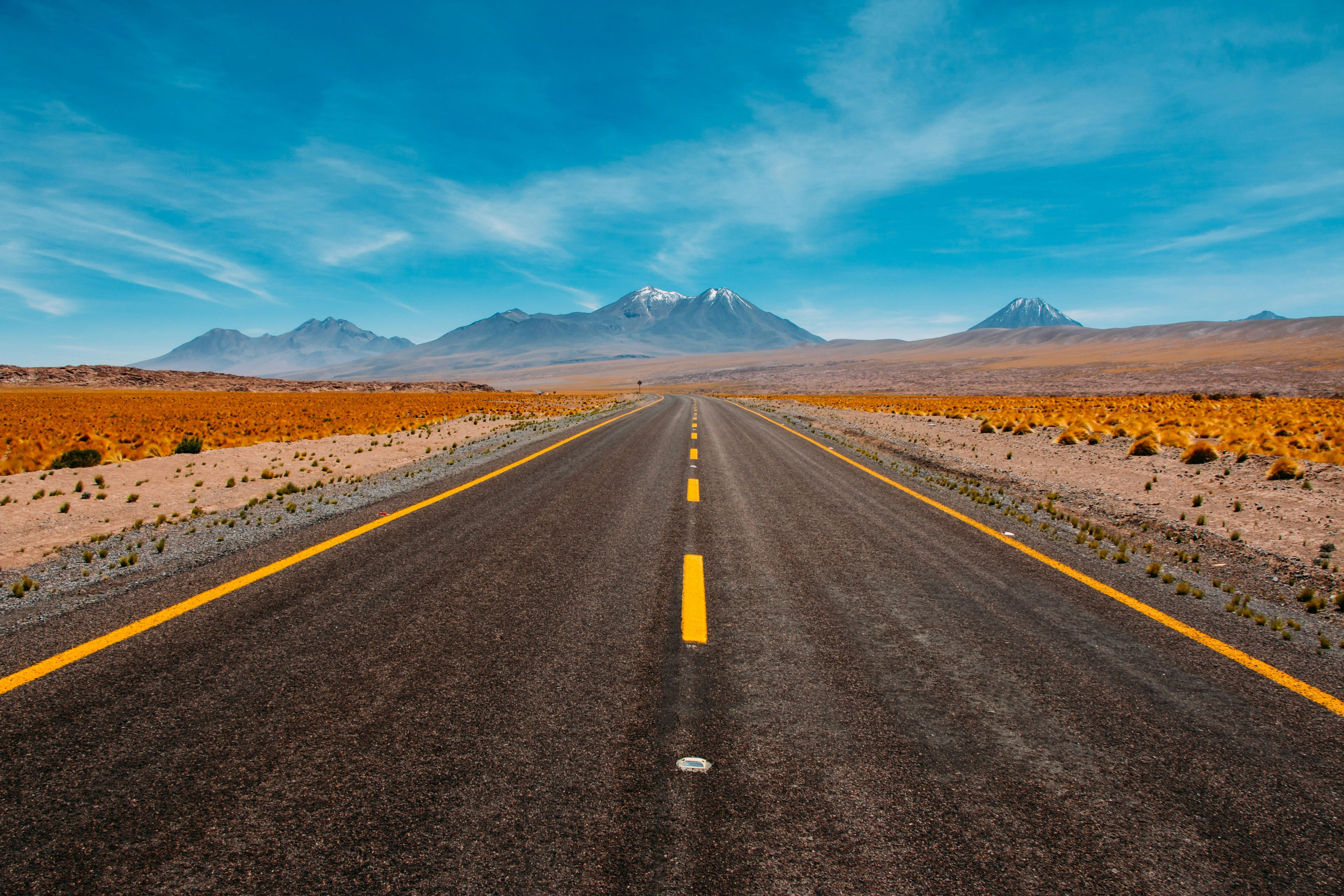 Empty desert road stretching toward snow-capped mountains